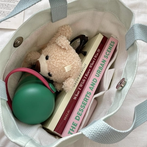 Detail view of large capacity canvas tote bag showing magnetic clasp and interior pocket