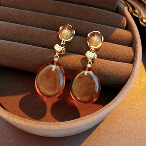 Macro detail of vintage amber resin teardrop earrings in a brown velvet jewelry gift box