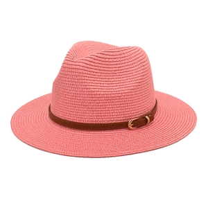 Close-up of pink woven straw Panama hat with brown leather band and gold buckle detail