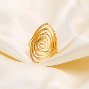 Macro detail of irregular spiral 18K gold plated titanium ring on silk fabric