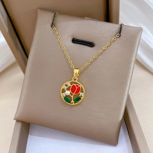 Detailed shot of gold plated rose pendant with red enamel on brown velvet cushion