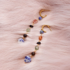 Macro view of long vintage bohemian earrings with natural stones and 18K gold plated tassels