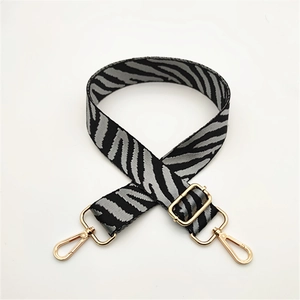 Detail of adjustable zebra print bag strap with high-quality gold metal swivel hooks