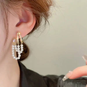 Detail view of gold tassel earrings with pearls and rhinestones on a female model