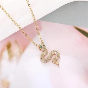 Luxurious gold snake pendant necklace with white crystals and green gemstone eyes