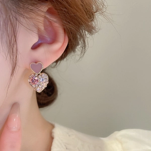 Detail of pink crystal heart drop earring with gold plating on model's ear