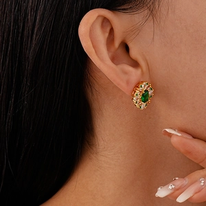 Vintage gold plated earrings with oval green zircon center on model's ear