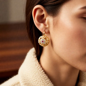 Macro shot of vintage gold hollow spherical earring with rubies and clear gemstones