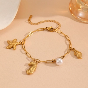 Detailed close-up of golden sea-themed charm bracelet with starfish, seahorse and pearls