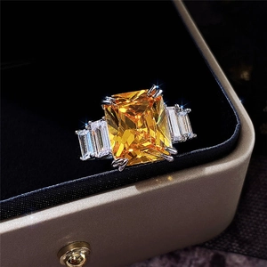 Detail of yellow rectangular radiant-cut gemstone ring with side baguettes in a gift box