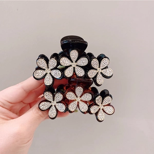 Dettaglio delle pinze per capelli a fiori con strass neri e marroni e bordi dorati
