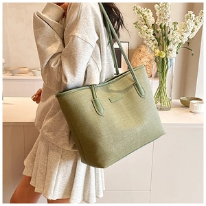 Detail of the grass green tote bag showing fine horizontal texture and slim shoulder straps