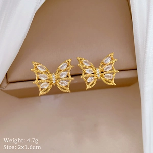 Gros plan sur les boucles d'oreilles papillon dorées avec zircons sur soie blanche