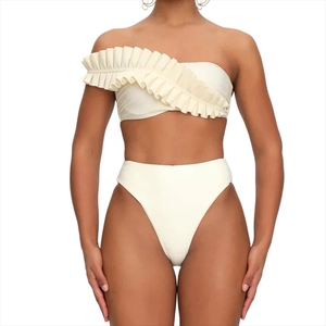 Detail of ruffled one-shoulder bikini top in cream white with premium layered fabric texture
