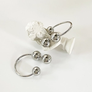 Detailed view of silver minimalist U-shaped earrings hanging on a white plaster statue