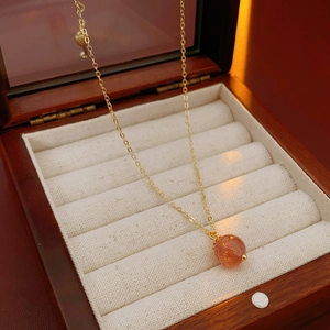 Detailed view of an orange spherical gemstone necklace in a luxury wooden jewelry box