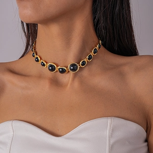 Close-up of vintage resin geometric choker with black circular gems on golden metal