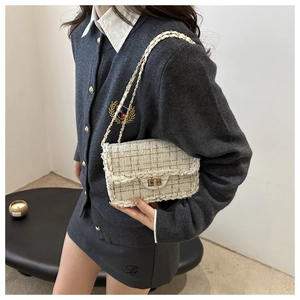 Detail of white tweed shoulder bag with gold chain strap and metal turn-lock on a model