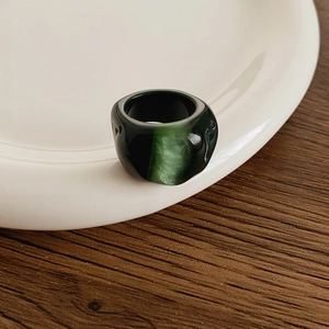 Detailed view of a chunky dark green gradient resin ring on a white ceramic plate