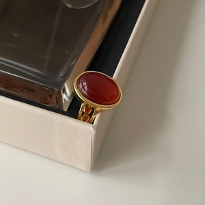 Dettaglio di una pietra di agata rossa ovale incastonata in un anello d'argento 925 dorato