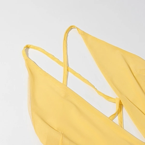 Detail of yellow backless dress featuring thin crisscross straps and fine mesh texture