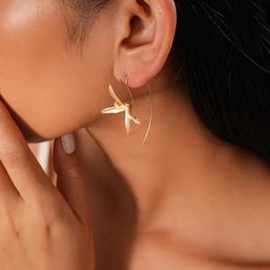 Macro shot of an elegant gold iris flower ear hook showing metallic texture and detail