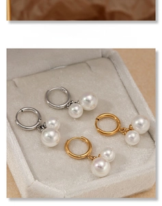 Detail of gold and silver double pearl drop earrings on a beige velvet jewelry tray
