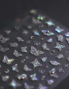 Macro shot of 3D holographic butterfly nail art stickers with pearl and diamond accents