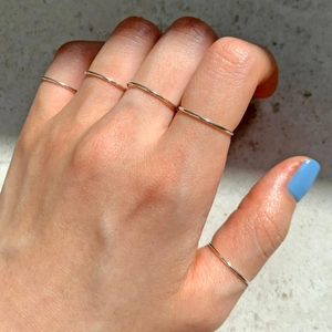 Macro shot of five minimalist S925 sterling silver thin rings worn on a hand