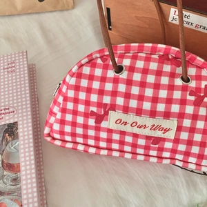 Detail of red and white checkered semicircular handbag with faux leather handles and bow