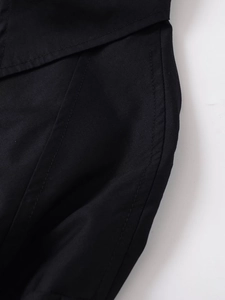 Detailed close-up of black utility shirt fabric showing matte texture and precision stitching