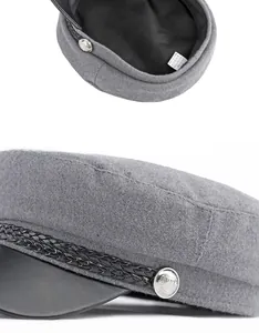 Detail of wool baker boy hat featuring black leather brim and silver side buttons