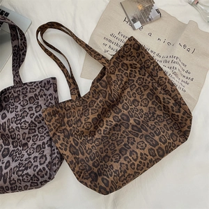 Flat lay of leopard print suede tote bags in brown and mauve with daily accessories