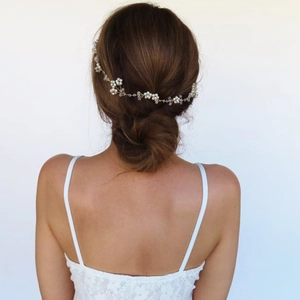 Detail of bridal pearl and crystal hair vine woven into a low bun on golden wire