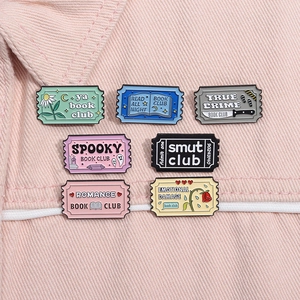 Set of pastel Book Club enamel pins in ticket shapes on pink denim jacket background