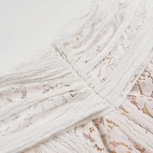 Detailed close-up of white lace fabric texture and concealed zipper on shoulder dress