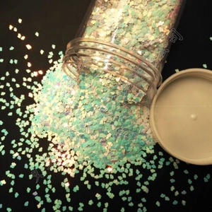 Macro shot of dreamlike cloud-shaped sequins in a clear jar on black background