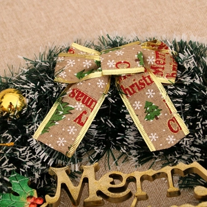 Close-up of a Christmas wreath featuring a Merry Christmas burlap bow and pine needles