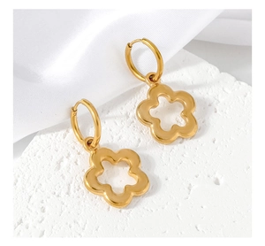 Detail of gold floral hoop earrings with hollow petals on a textured white stone base