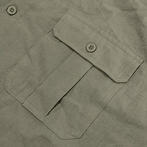 Detail of army green linen shirt showing a buttoned flap pocket and twill texture