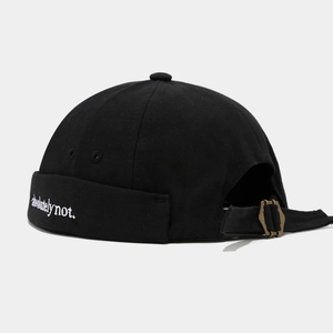 Detail of black Miki hat featuring white embroidery and an adjustable bronze metal buckle