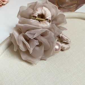 Détail de la pince à cheveux fleur en organza champagne avec pendentif perle