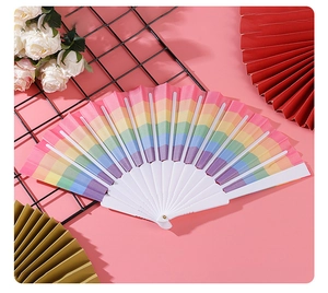 Foldable rainbow stripe fan with white plastic frame displayed on a black mesh stand