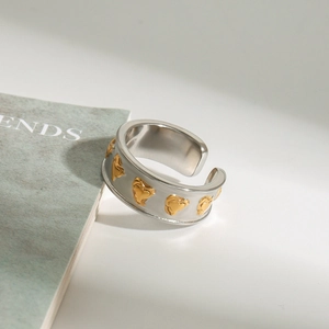 Détail de la bague ajustable bicolore en acier avec motifs de cœurs dorés