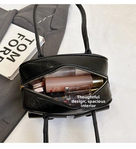 Detail view of the spacious black glossy handbag interior holding cosmetics and perfume