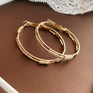 Macro detail of gold double-layered hoop earrings with sparkling white rhinestones