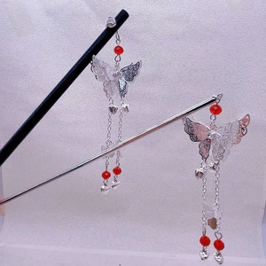Detail of silver butterfly tassel hairpin with red beads and hollow metal wing patterns