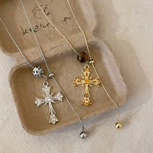 Detail of gold and silver tiger eye cross necklaces with snake chains on a tray