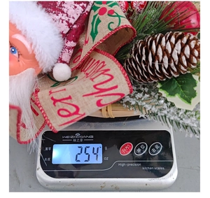 Detail view of a 254g Christmas Santa wreath showing actual product weight on a scale