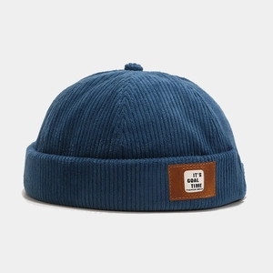 Detail of navy corduroy docker cap with IT'S GOAL TIME leather patch and ribbed texture